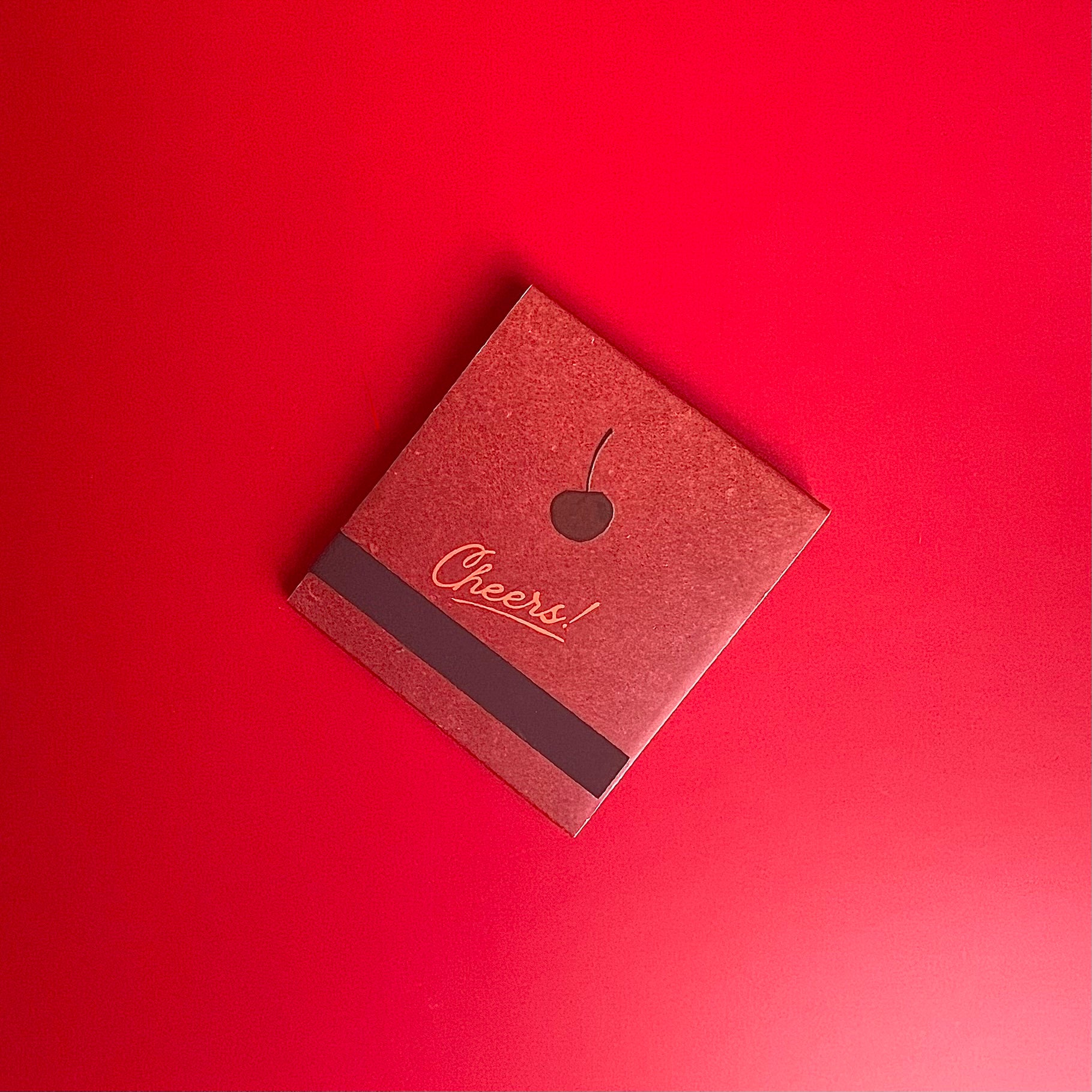 The back of the Manhattan cocktail matchbook featuring a cherry and match-striking bar