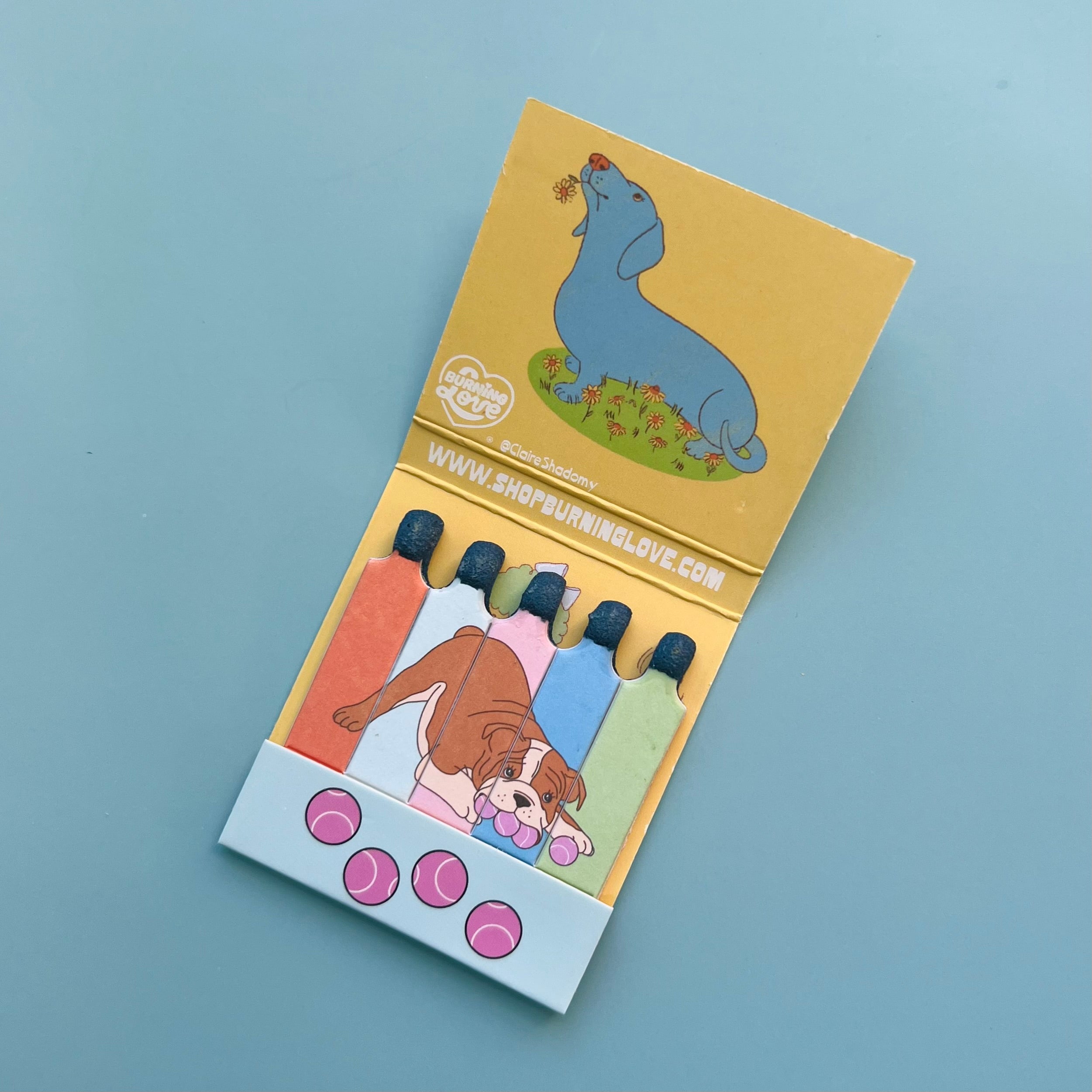 Inside of dog matchbook showing a stylized Dachshund and a Boxer on the matchsticks themselves