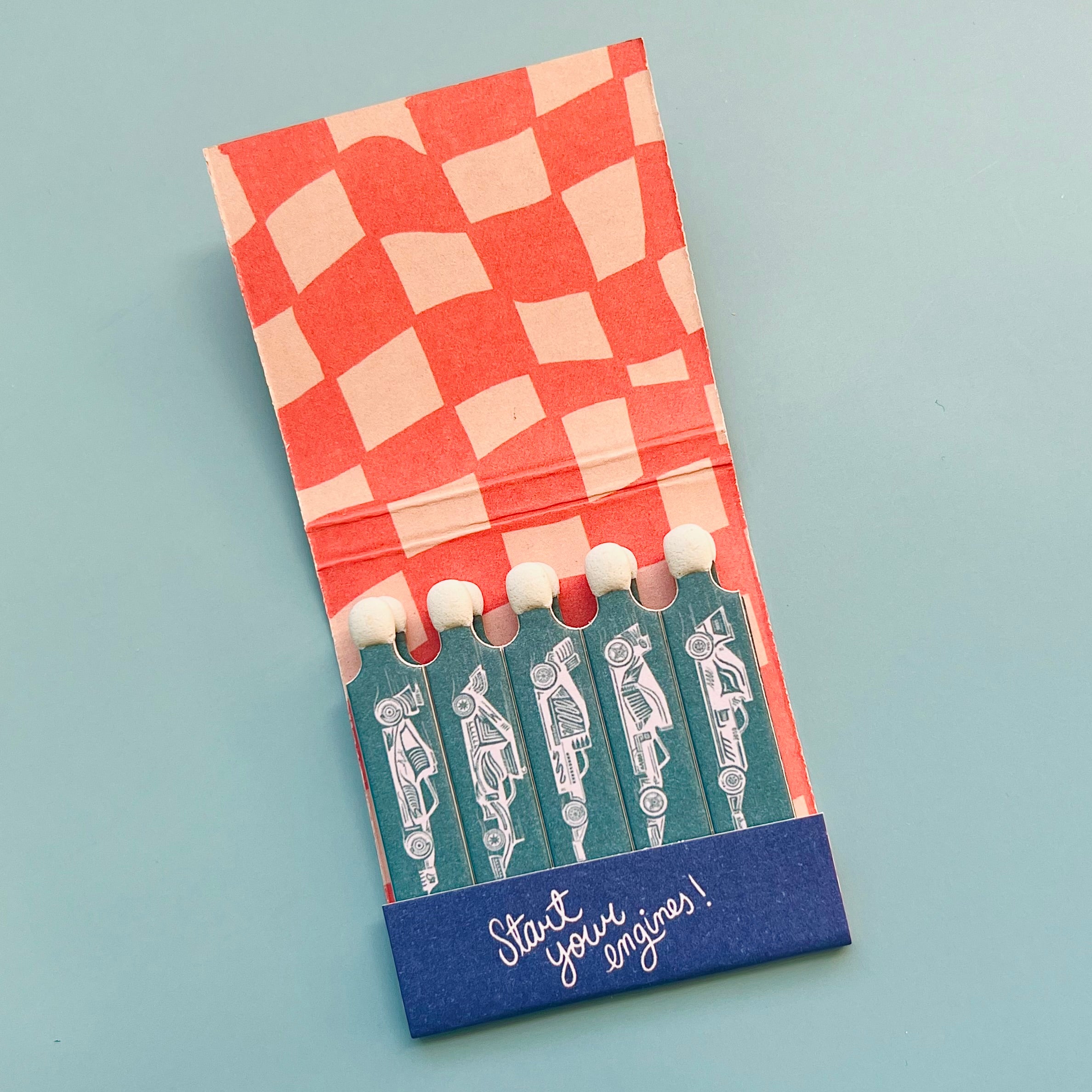 Inside of race car matchbook showing a red/coral check pattern and drawings of race cars on each match