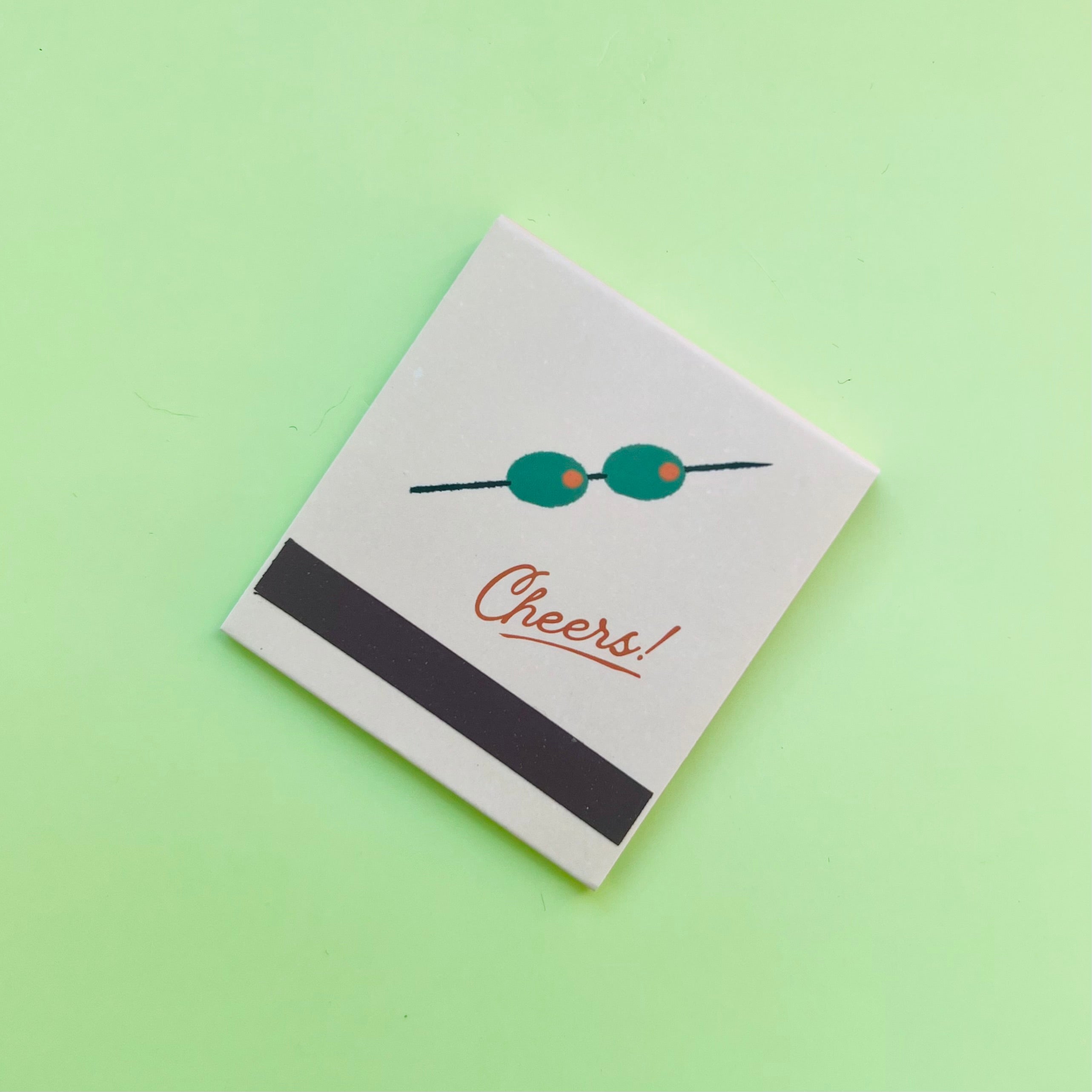 Back of martini matchbook depicting olives on a skewer and the match-striking bar
