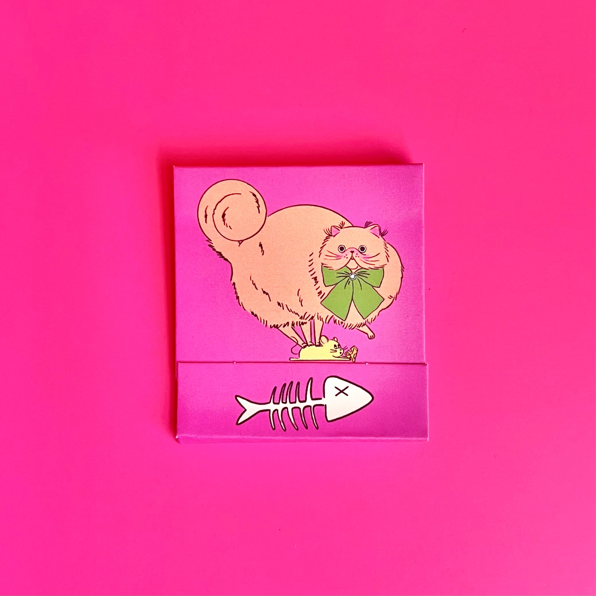 Front of cat matchbook featuring an orange cat with fish bones on the bottom 