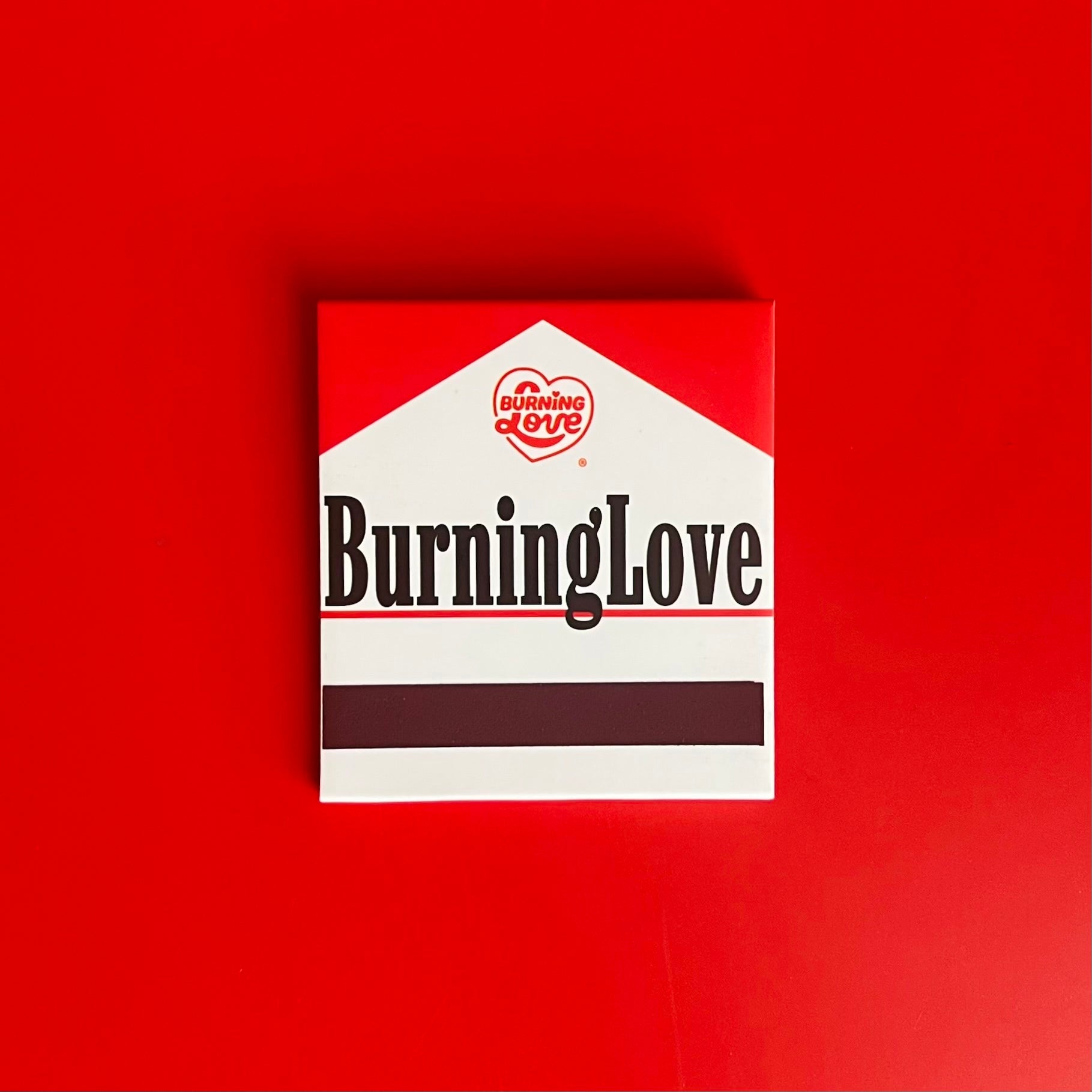 Back of Cigarette Matchbook depicting the words “Burning Love” with the match-striking bar on the bottom 