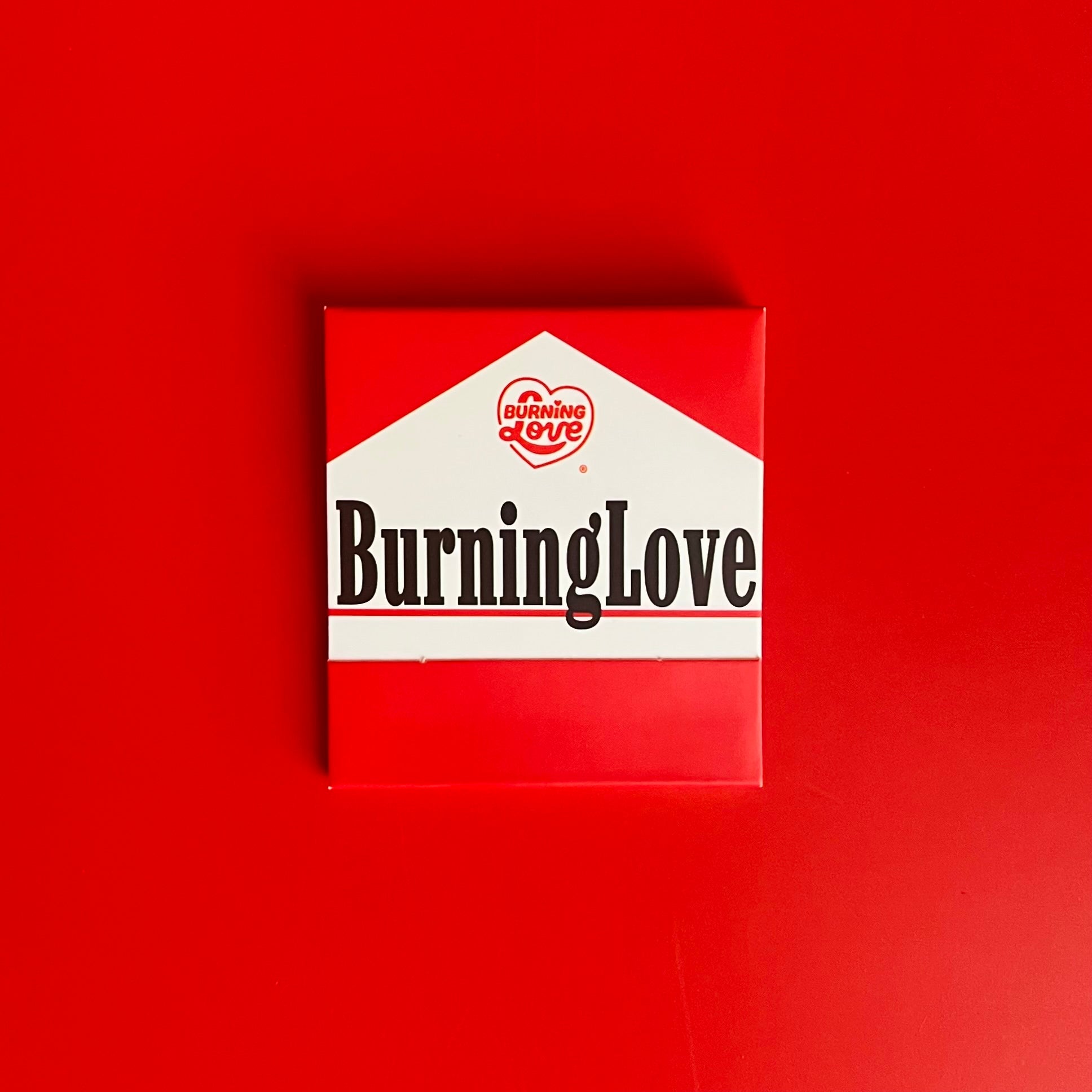 Front of cigarette matchbook made to look like Marlboro Reds but instead with the words “Burning Love”