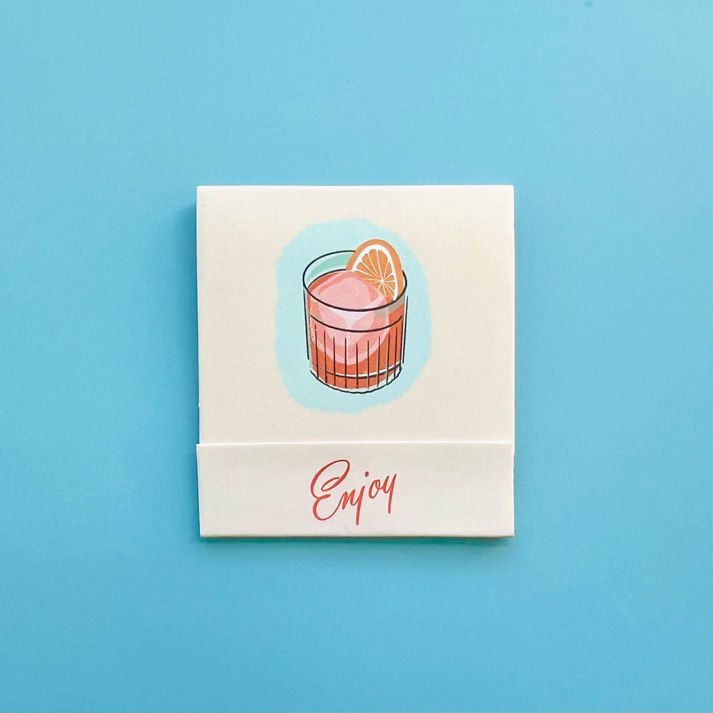 Front of Negroni matchbook featuring a drawing of the cocktails and the word “Enjoy”