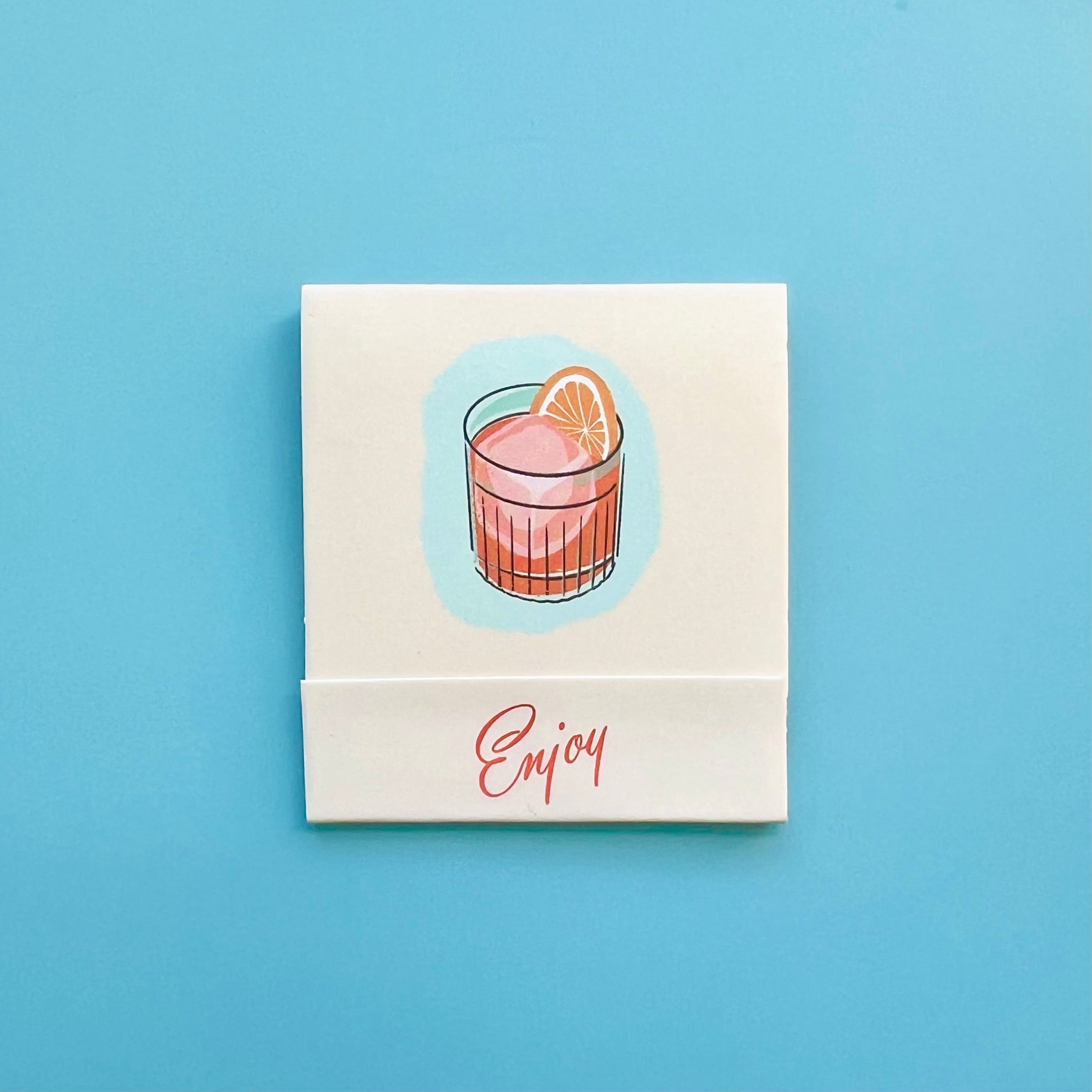 Front of Negroni matchbook featuring a drawing of the cocktails and the word “Enjoy”