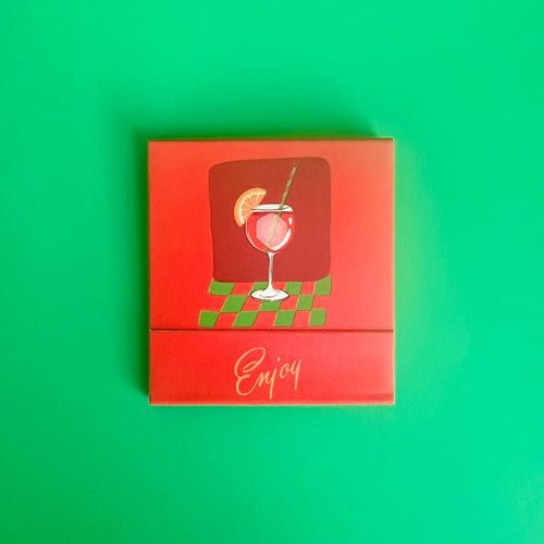 The front of the Aperol Spritz matchbook depicting a drawing of the orange cocktail in a wine glass